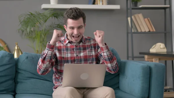 Man with Laptop Celebrating Success on Sofa