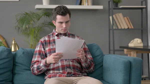 Man Reading Documents on Sofa