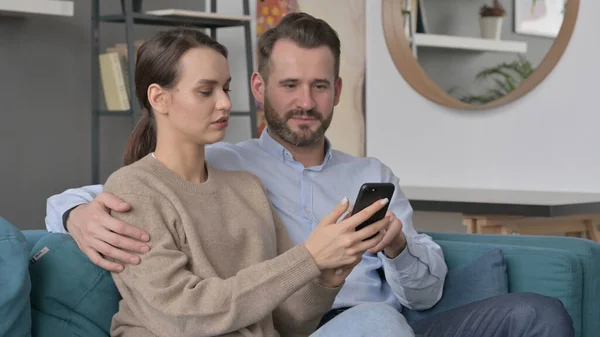 Portrait of Couple using Smartphone While Sitting on Sofa — Stock Photo, Image