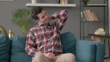 Kanepede oturan adamın boynu ağrıyor. 