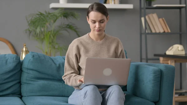 Женщина работает на ноутбуке на диване — стоковое фото