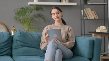 kanepede otururken tablet kullanan kadın 