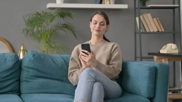 Vrouw met behulp van smartphone op sofa — Stockfoto