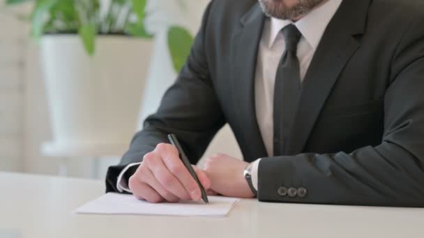 Закрытие среднего возраста бизнесмена, пишущего на бумаге ручкой — стоковое видео