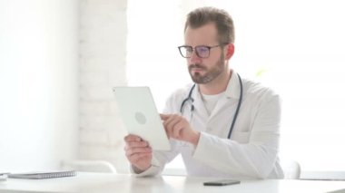 Doctor using Tablet while Sitting in Office