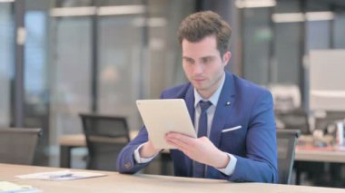 Ofiste otururken Tablet kullanan İşadamı