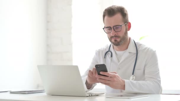 Doctor using Smartphone while using Laptop in Office — Video Stock