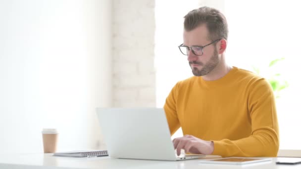 Uomo che punta alla fotocamera durante l'utilizzo del computer portatile in ufficio — Video Stock