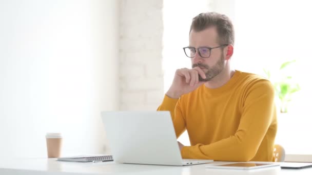 Homem Pensando enquanto trabalhava no laptop no escritório — Vídeo de Stock