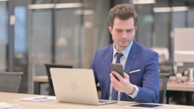 Ofiste dizüstü bilgisayar kullanırken telefonda konuşurken işadamı