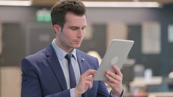 Retrato de videollamada en tableta por un hombre de negocios en la oficina — Vídeos de Stock