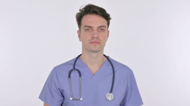 Grave jovem médico olhando para a câmera no fundo branco — Vídeo de Stock
