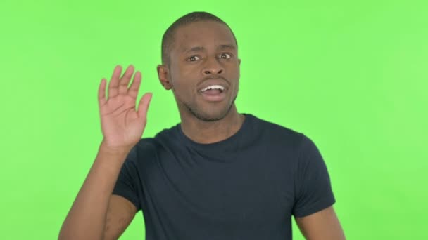 Молодой афроамериканец подслушивает тайно на зеленом фоне — стоковое видео