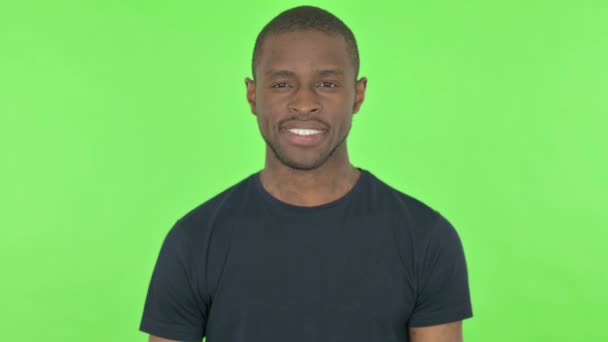 Молодой африканский человек улыбается на зеленом фоне — стоковое видео