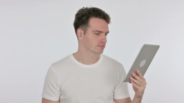 Mladý muž reaguje na ztrátu na tabletu na bílém pozadí — Stock video