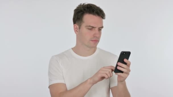 Молодой человек просматривает смартфон на белом фоне — стоковое видео