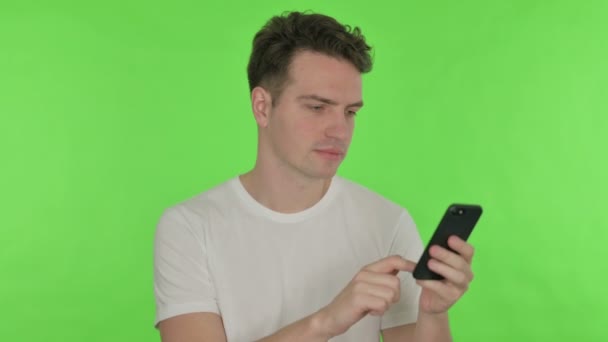 Mladý muž procházení Smartphone na zeleném pozadí — Stock video