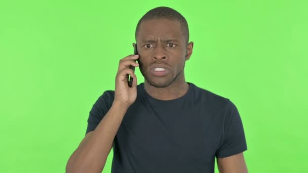 Irritado jovem africano falando no telefone em fundo verde — Vídeo de Stock