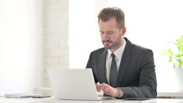 Junger Geschäftsmann lächelt mit Laptop im Büro in die Kamera — Stockvideo