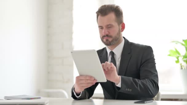 Joven Empresario usando Tablet mientras está sentado en la oficina — Vídeos de Stock