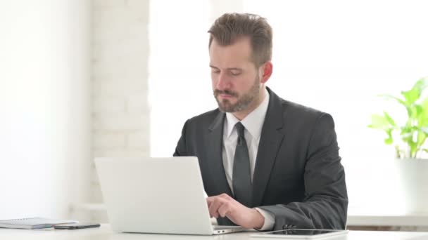 Молодой бизнесмен кашляет при использовании ноутбука в офисе — стоковое видео