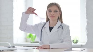 Klinikte otururken Başparmağını gösteren kadın doktor.