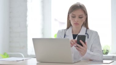 Klinikte dizüstü bilgisayar kullanırken Smartphone kullanan kadın doktor 