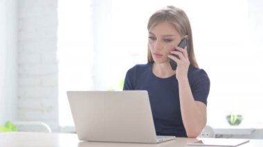 Laptop kullanırken Telefonda Konuşan Genç Kadın