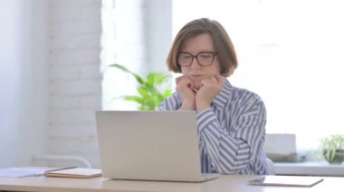 Dizüstü bilgisayarda çalışırken düşünen yaşlı kadın.