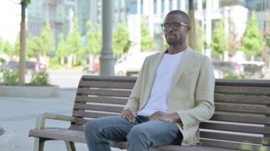 Bench Outdoor 'da oturduktan sonra Afrika kökenli Amerikalı adam ayakta ve gidiyor.