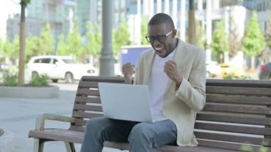 Afro-Amerikalı Adam, Bench 'te otururken Laptop' ta Başarı Kutlaması