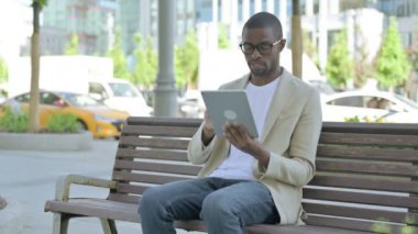 Benç 'te otururken Tablet kullanan Afro-Amerikan Adam