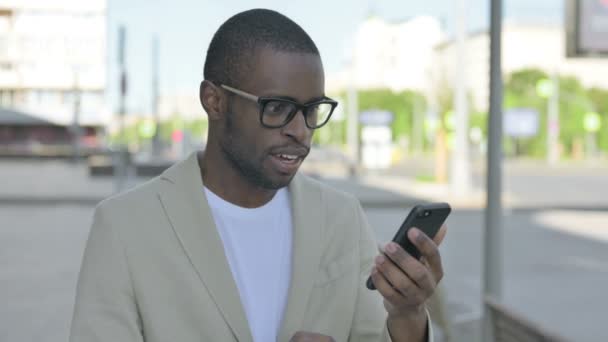 African American Man Γιορτάζοντας Online Επιτυχία Στο Smartphone Outdoor — Αρχείο Βίντεο