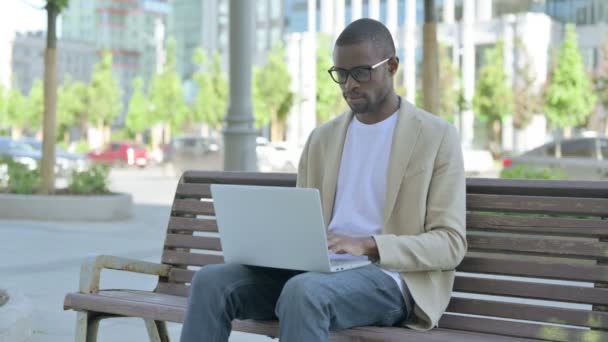 ベンチに座っている間にラップトップを使用して首の痛みを持つアフリカ系アメリカ人男性 — ストック動画