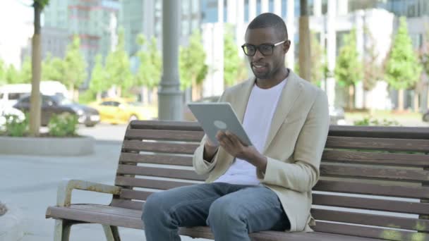 Афроамериканец Празднует Победу Интернете Планшете Сидя Скамейке — стоковое видео