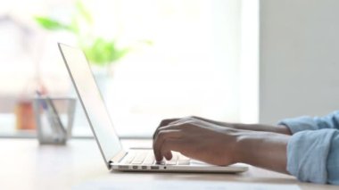 Side View of African Man Typing on Laptop Keyboard