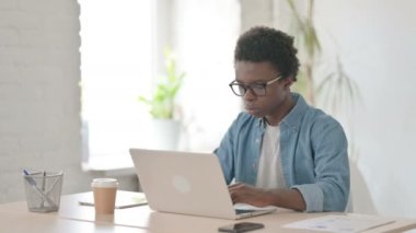 Ofiste dizüstü bilgisayar kullanırken boynu ağrıyan Afrikalı adam 