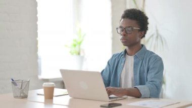 Ofiste Dizüstü bilgisayar kullanan Afrikalı Adam 'dan Baş Parmak İndirme 