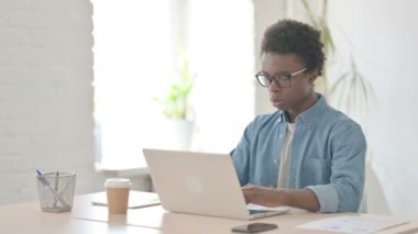 Ofiste dizüstü bilgisayar kullanırken Afrikalı Adam öksürüyor 