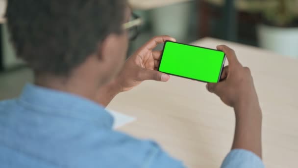 アフリカ人男性クロマ画面でスマートフォンを見て — ストック動画