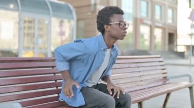 Afrikalı Adam Bench Outdoor 'da otururken sırt ağrısı çekiyor