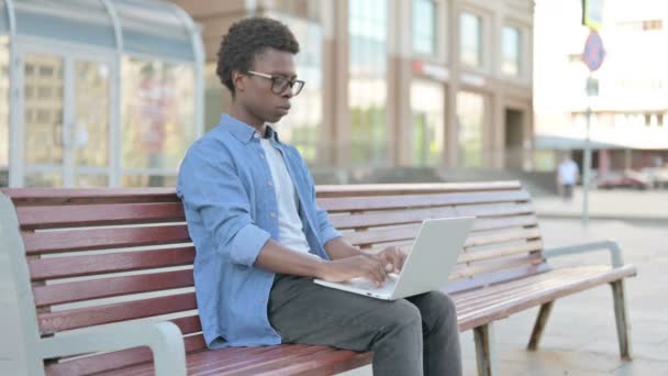 Африканський Чоловік Головним Болем Використовуючи Ноутбук Сидячи Відкритому Повітрі Лавці — стокове відео