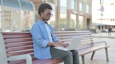 Thinking African Man Using Laptop while Sitting Outdoor on Bench