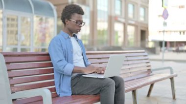 African Man Reacting to Loss on Laptop while Sitting Outdoor on Bench