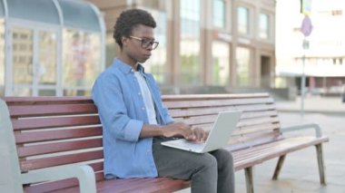 African Man Talking on Video Call while Sitting Outdoor on Bench