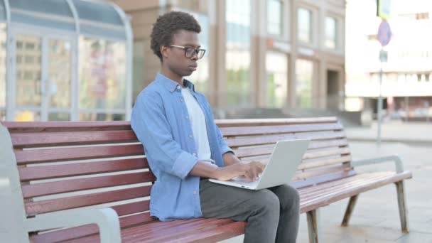 非洲男子关闭笔记本电脑后离开长凳 — 图库视频影像