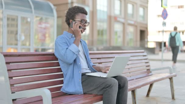 Африканский Мужчина Разговаривает Телефону Пользуется Телефоном Сидя Скамейке — стоковое видео