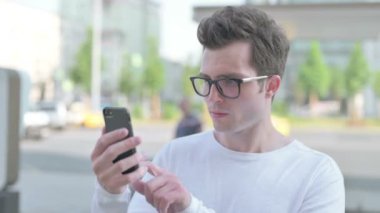 Casual Man Celebrating Online Success on Smartphone Outdoor