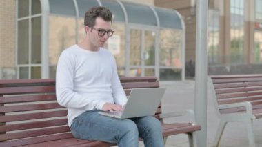Casual Man Celebrating Success on Laptop while Sitting Outdoor on Bench