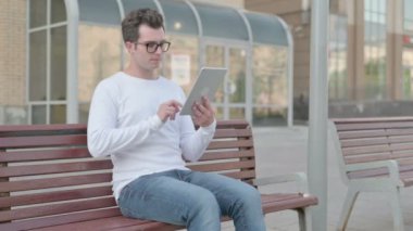 Casual Man Celebrating Online Win on Tablet while Sitting Outdoor on Bench